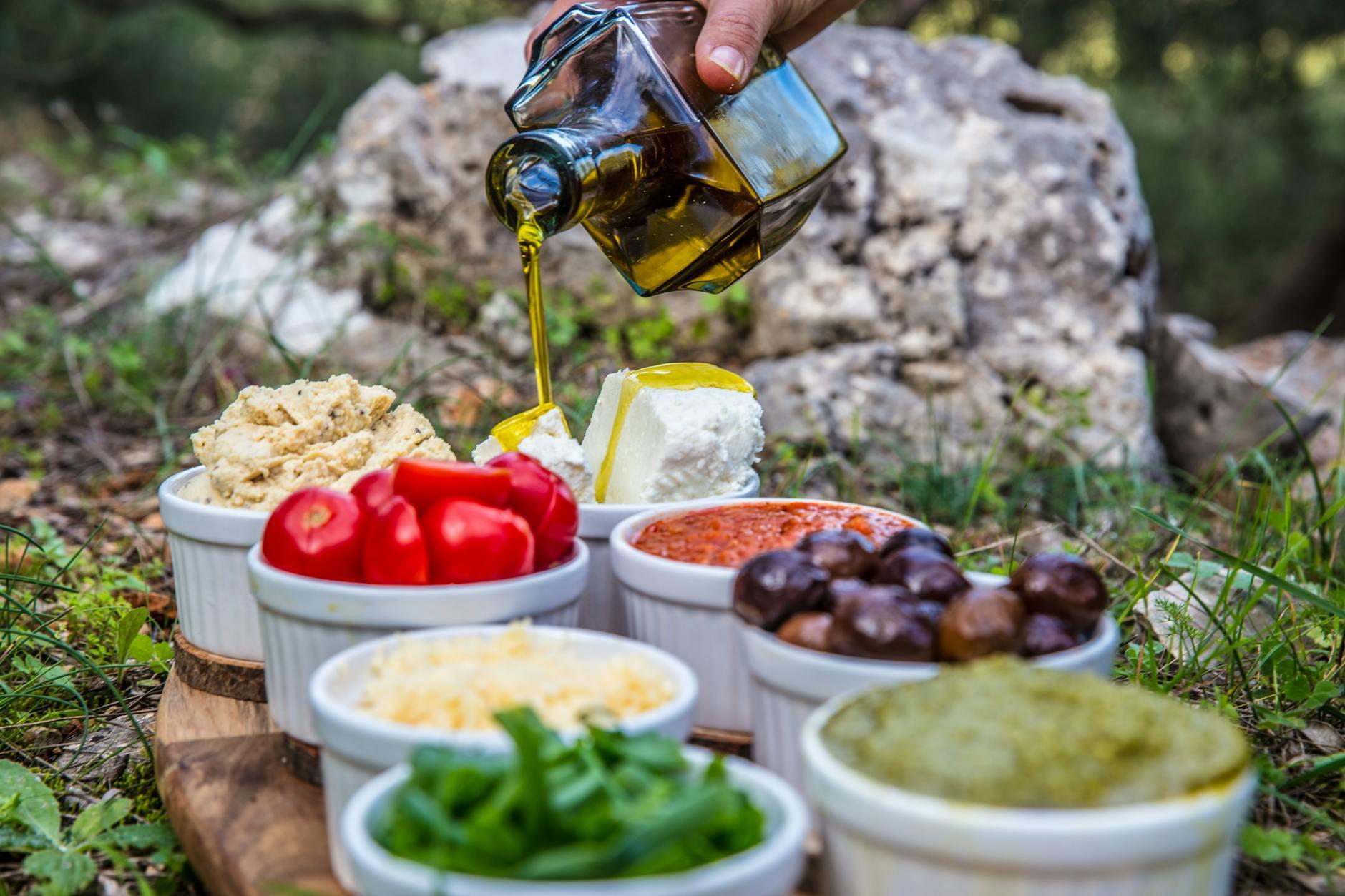 Table de cuisine méditerranéenne avec huile d'olive, dattes et herbes fraîches illustrant le régime Tayibat