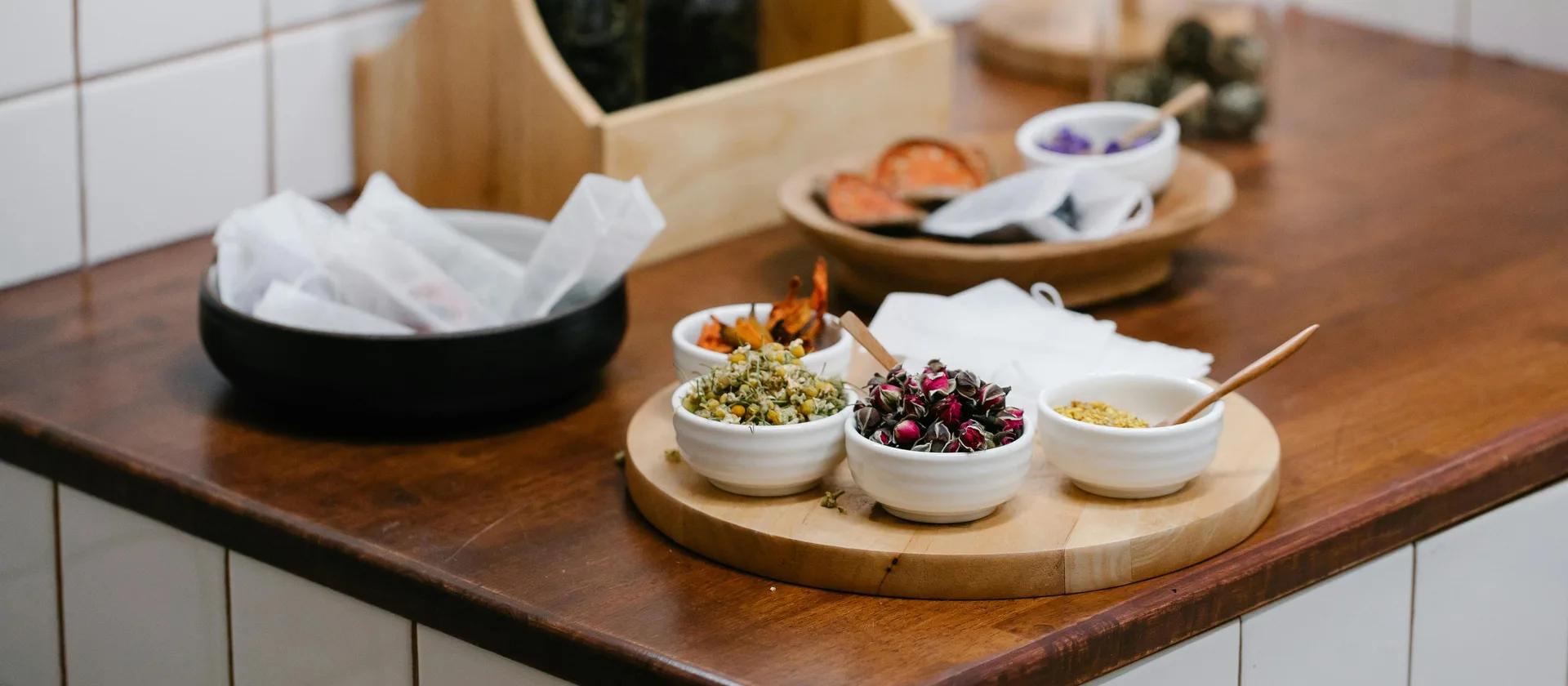 Bols d'herbes et ingrédients sur comptoir en bois, photographie culinaire moderne.